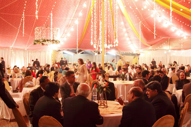 A wedding party with lights and decorations under a marquee.