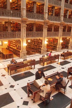 People at different desks in the library.