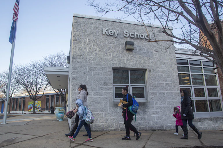 Parents and children walk next to a school building