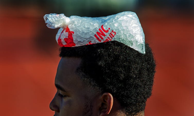 A young man with a bag of ice on his head.