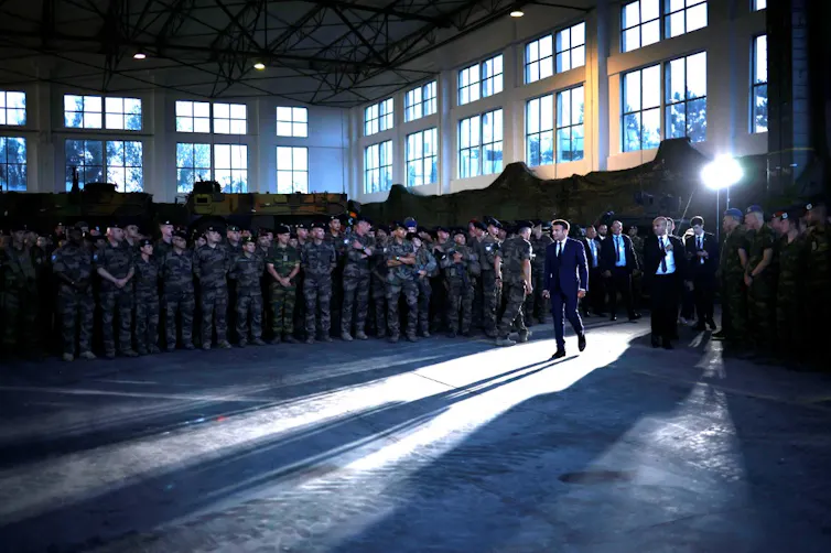 Emmanuel Macron dans une grande salle devant des soldats en uniforme
