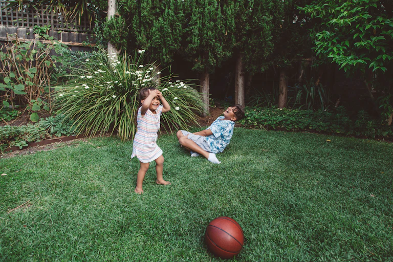 Two First Nations children play in a backyard laughing.
