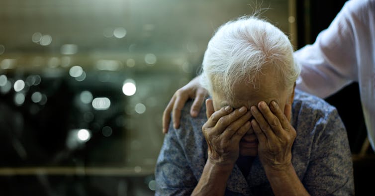 person comforting older person, who has head in hands