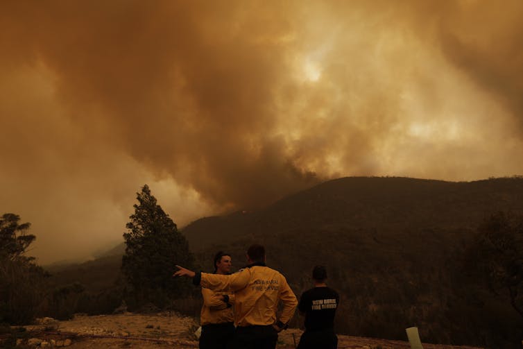fire officials stand in front of smoke-filled landscape