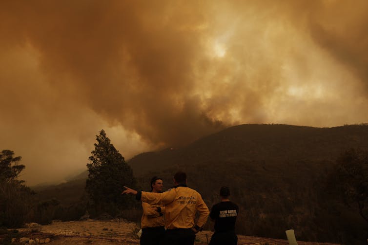 fire officials stand in front of smoke-filled landscape