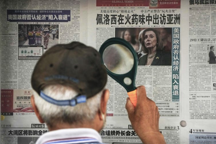 Man reading a wall-poster newspaper