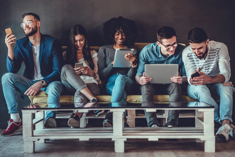 Group of people sitting on a sofa using devices