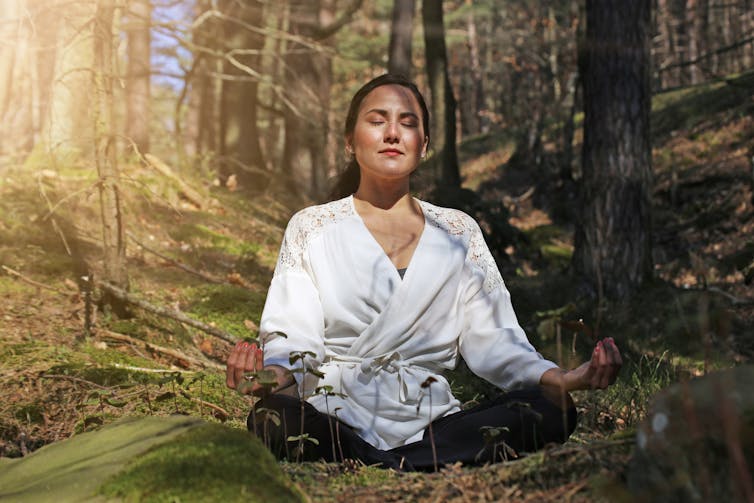 Lady meditates in forest
