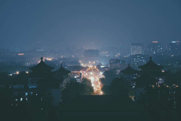 A long-distance photo of a city at night illuminated with lights.