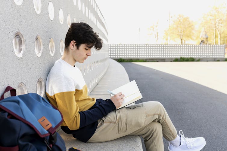 Young man writing in journal outdoors