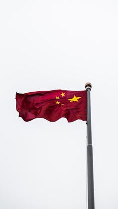 The red Chinese flag with gold stars flutters in the wind.