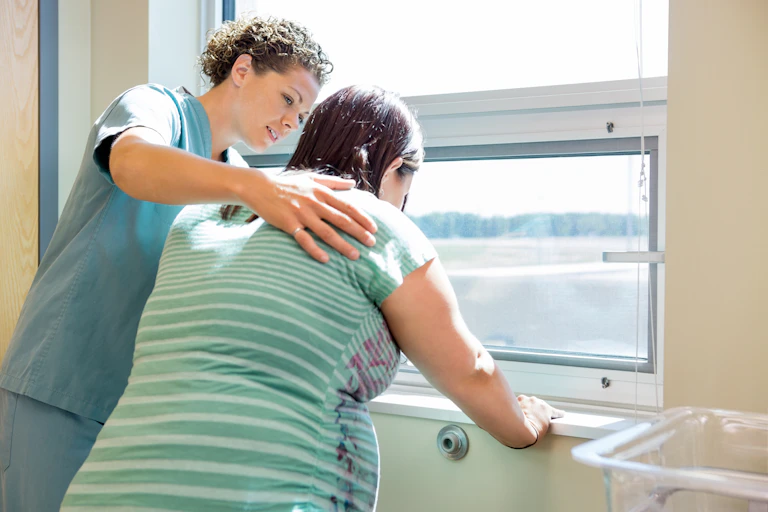 Midwife puts her hand on a birthing woman's back