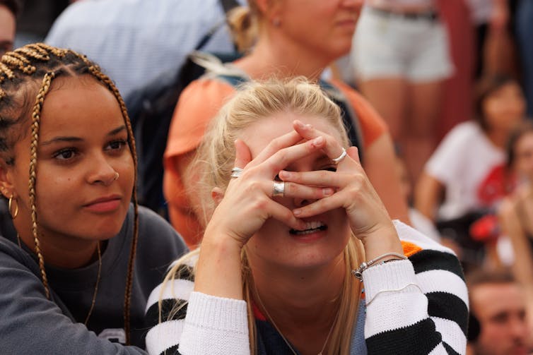Two women, one looking through her fingers