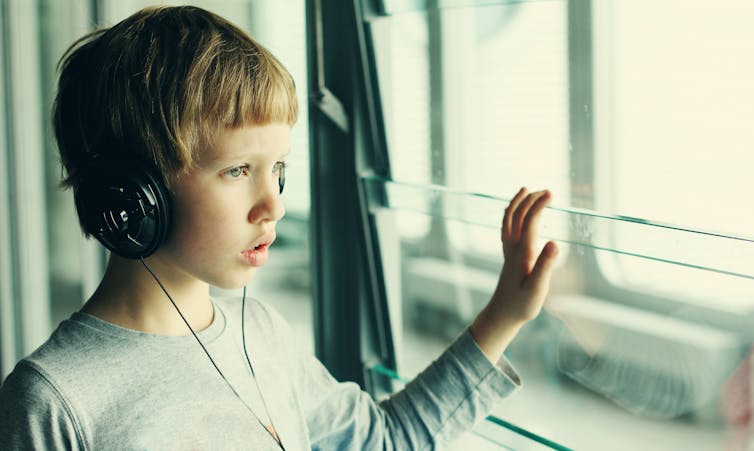 Boy wearing headphones looks out of a window