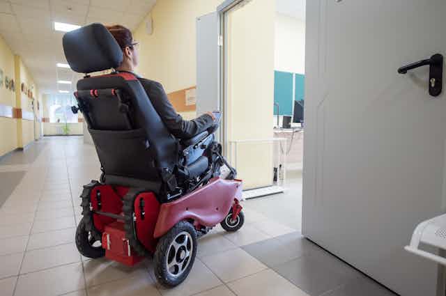 Una persona en silla de ruedas eléctrica entrando en un aula.