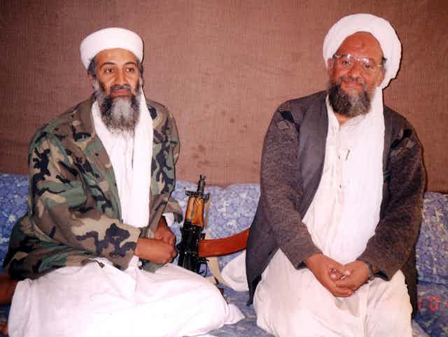 Osama bin Laden sits with his then adviser Ayman al-Zawhir, both wearing traditional Islamic dress.