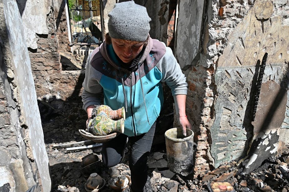Une femme emporte deux petits vases des ruines d'un bâtiment