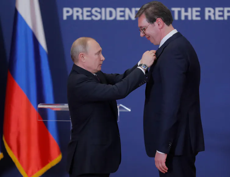 Vladimir Putin pins a medal on the chest of the Serbian president Aleksandar Vucic