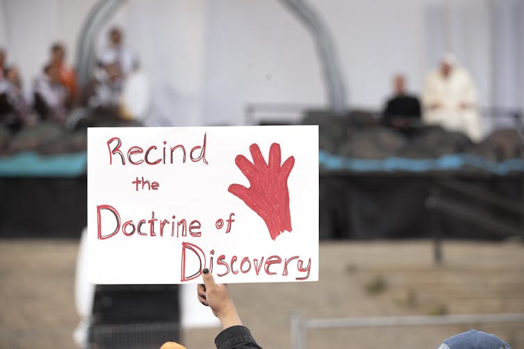 A sign reads 'recind the doctrine of discovery'
