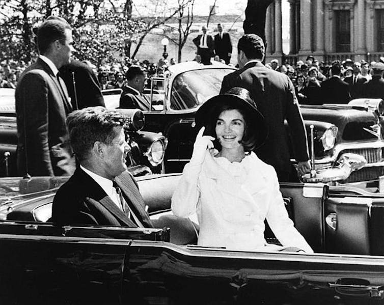 Black and white photo of JFK and Jackie Kennedy in an open top motorcade