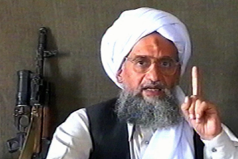 Al-Zawahiri s'exprime lors d'une allocution. Un fusil d'assaut est en arrière plan.