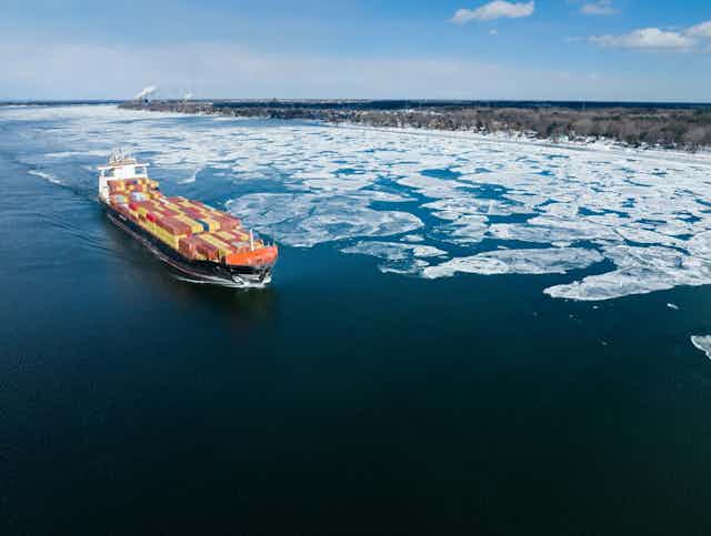 A full container ship travels on a partially frozen body of water