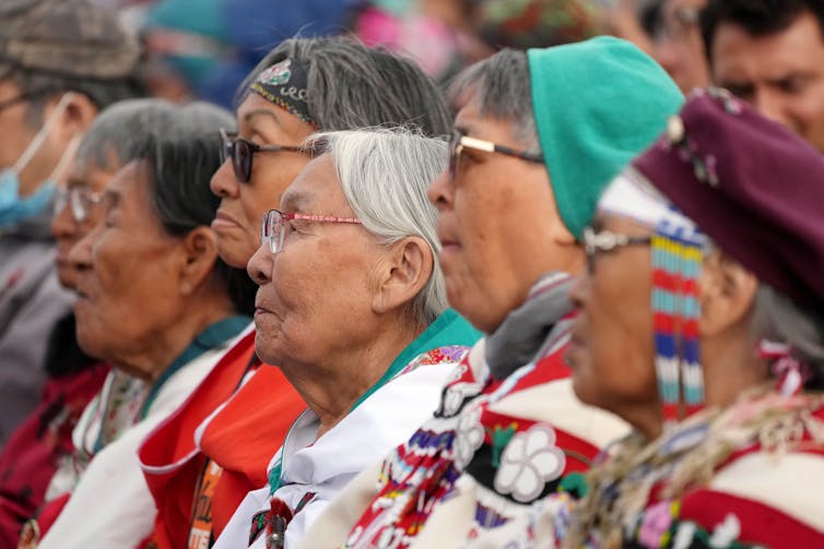 Elders seen in a crowd listening.