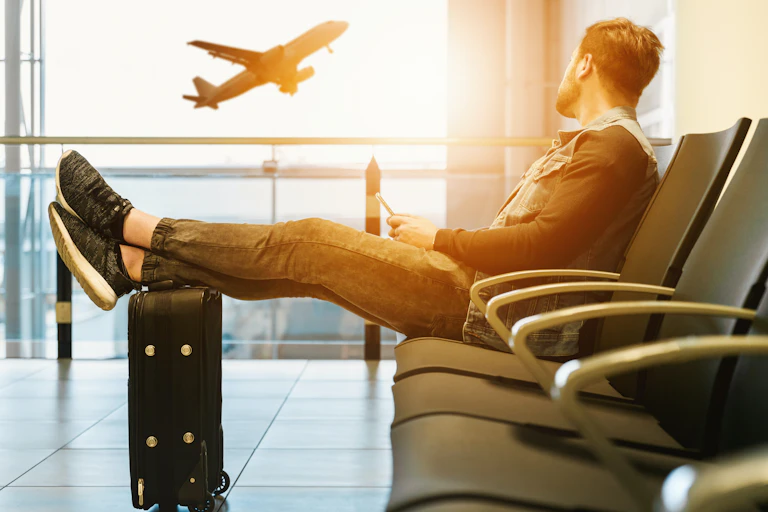 Man sitting on a chair in the airport with his feet on luggage