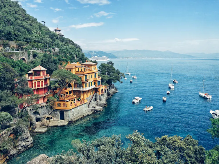A mountain with homes embedded along the side is pictured by the sea