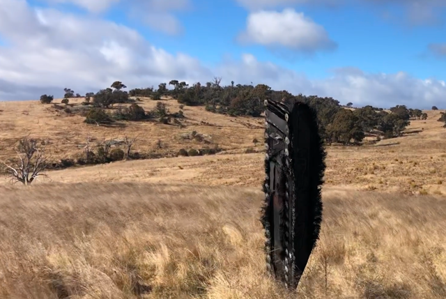 A piece of space debris standing among barren farmland.