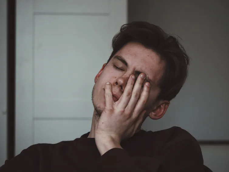 Man holds his hand to his face, feeling unwell