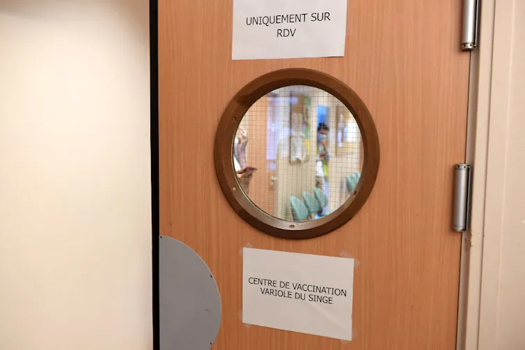 Porte d’un centre de soin à Paris avec un panneau indiquant « centre de vaccination variole du singe », « sur rendez-vous uniquement »