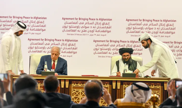 US Special Representative for Afghanistan Reconciliation Zalmay Khalilzad and Taliban co-founder Mullah Abdul Ghani Baradar sign the US-Taliban peace agreement during a ceremony in Doha, Qatar, 29 February 2020.