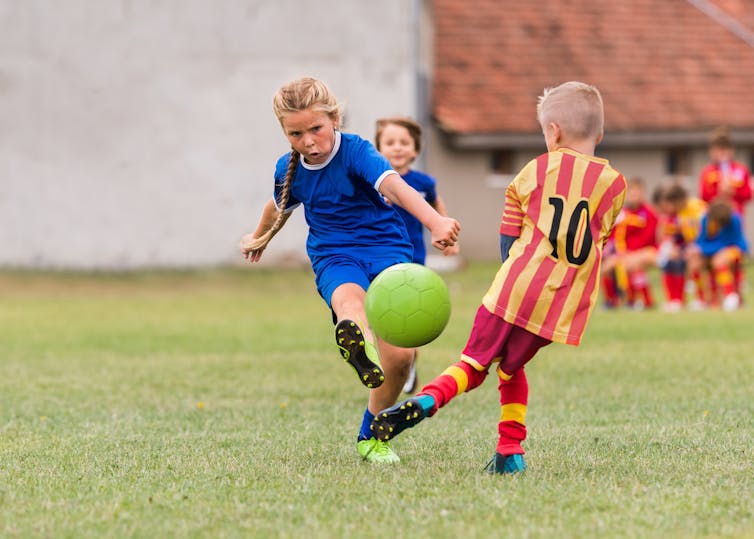 Girl and boy play football.