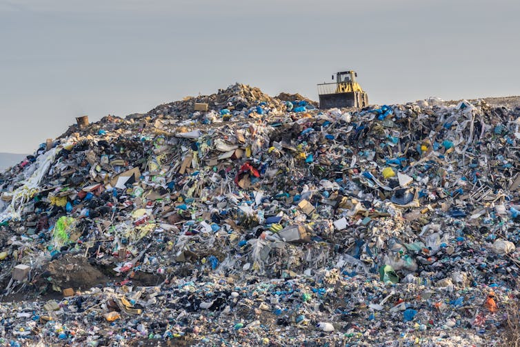 Site machinery sat on top of a pile of waste at a landfill.