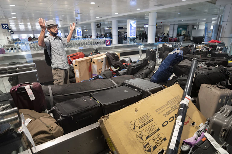 homme avec les bras levés devant une pile de bagages à l'aéroport