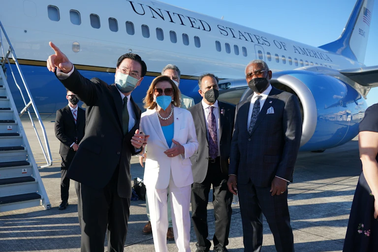 5 masked adults are shown standing together in formal clothing outside the US government airplane on a tarmac.