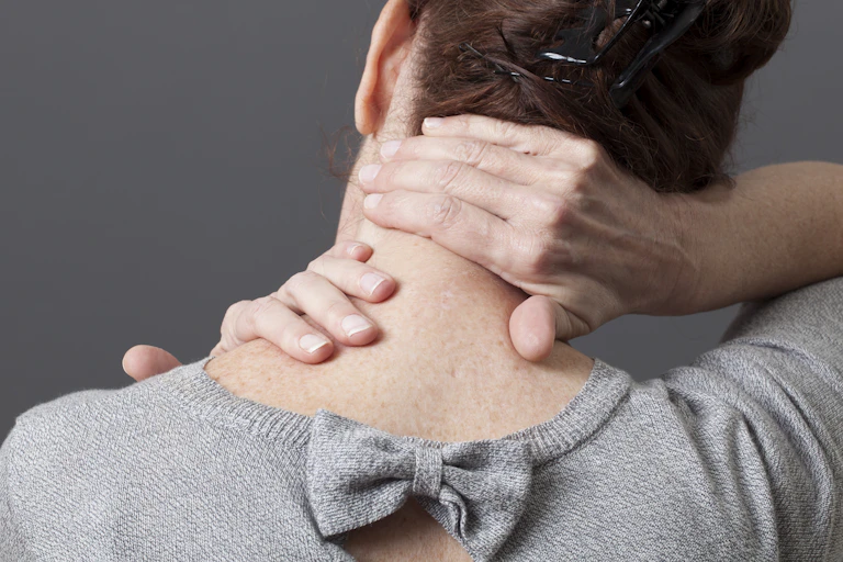back of woman's upper body, leaning head and massaging neck with hands