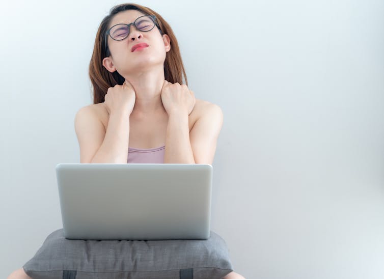 mujer joven en la computadora portátil llega hasta el cuello con incomodidad
