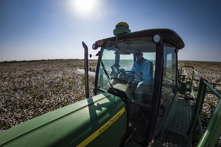 a man drives a tractor with a dome-like structure on its roof over a massive field