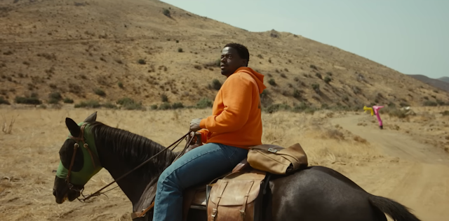 A screenshot from the movie 'Nope' of the character OJ Haywood sitting on a horse 