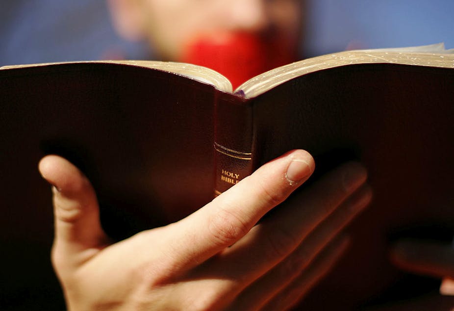 A close-up photo of a Bible held by a person with red duct tape over their mouth.