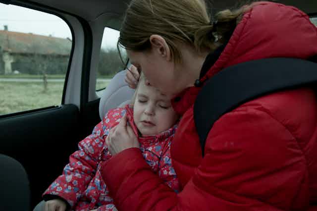 Mother comforts young child in car