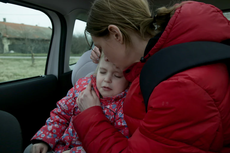 Mother comforts young child in car
