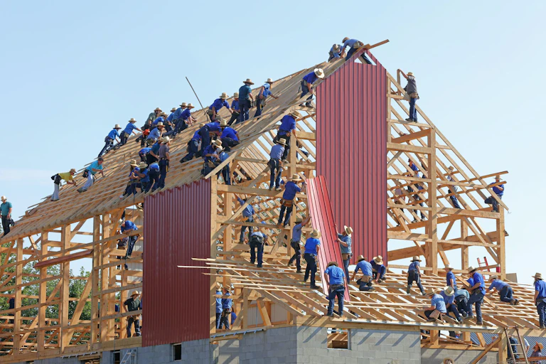 Lots of construction workers putting cladding on a building