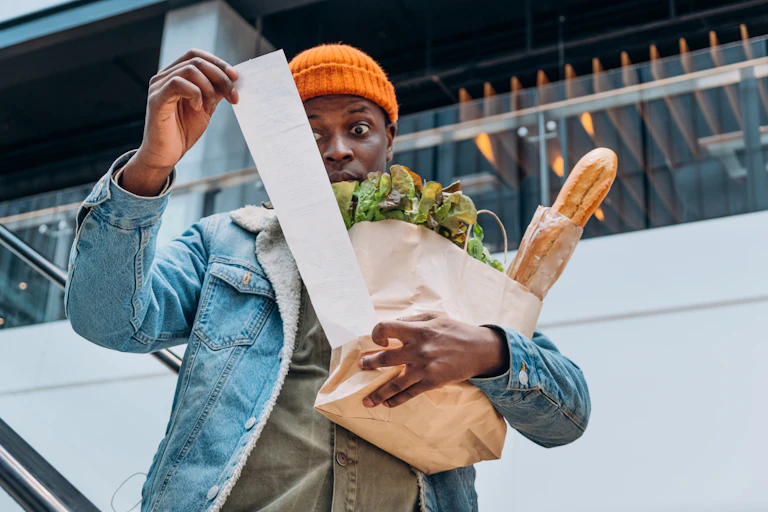 Shocked man with groceries and receipt