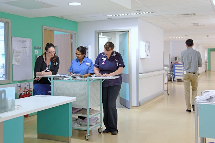 Three nurses having a discussion on a hospital ward