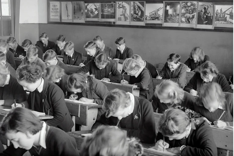 Una clase de alumnos uniformados se inclina sobre sus pupitres mientras hace un examen.