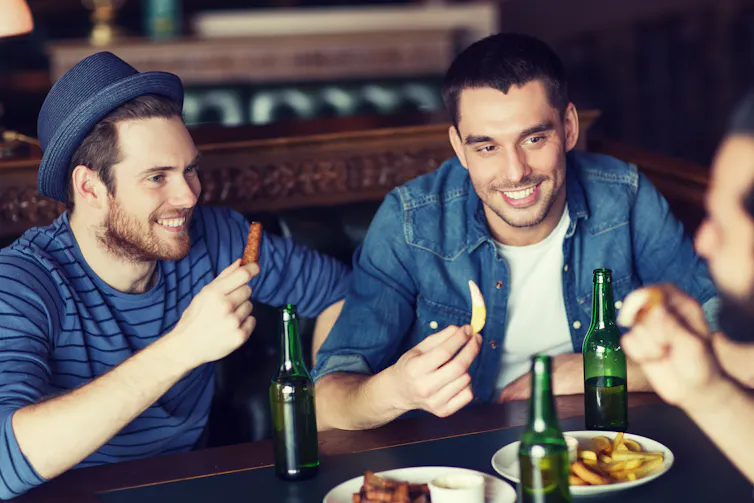 A group of young men drink beers in a pub.