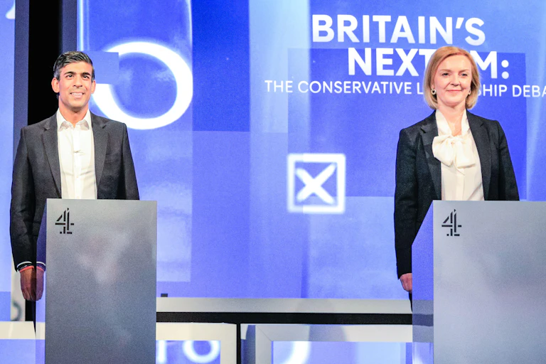 Rishi Sunak and Liz Truss debating at podiums.